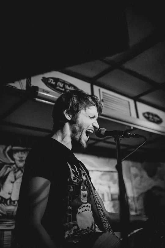Ein Gitarrist von Falke Collective singt ins Mikrofon auf der Innenbühne.