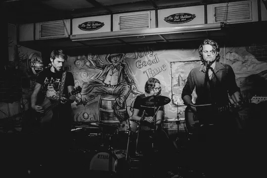 Falke Collective mit Gitarren und Schlagzeug bei einem Auftritt auf einer kleinen Innenbühne.